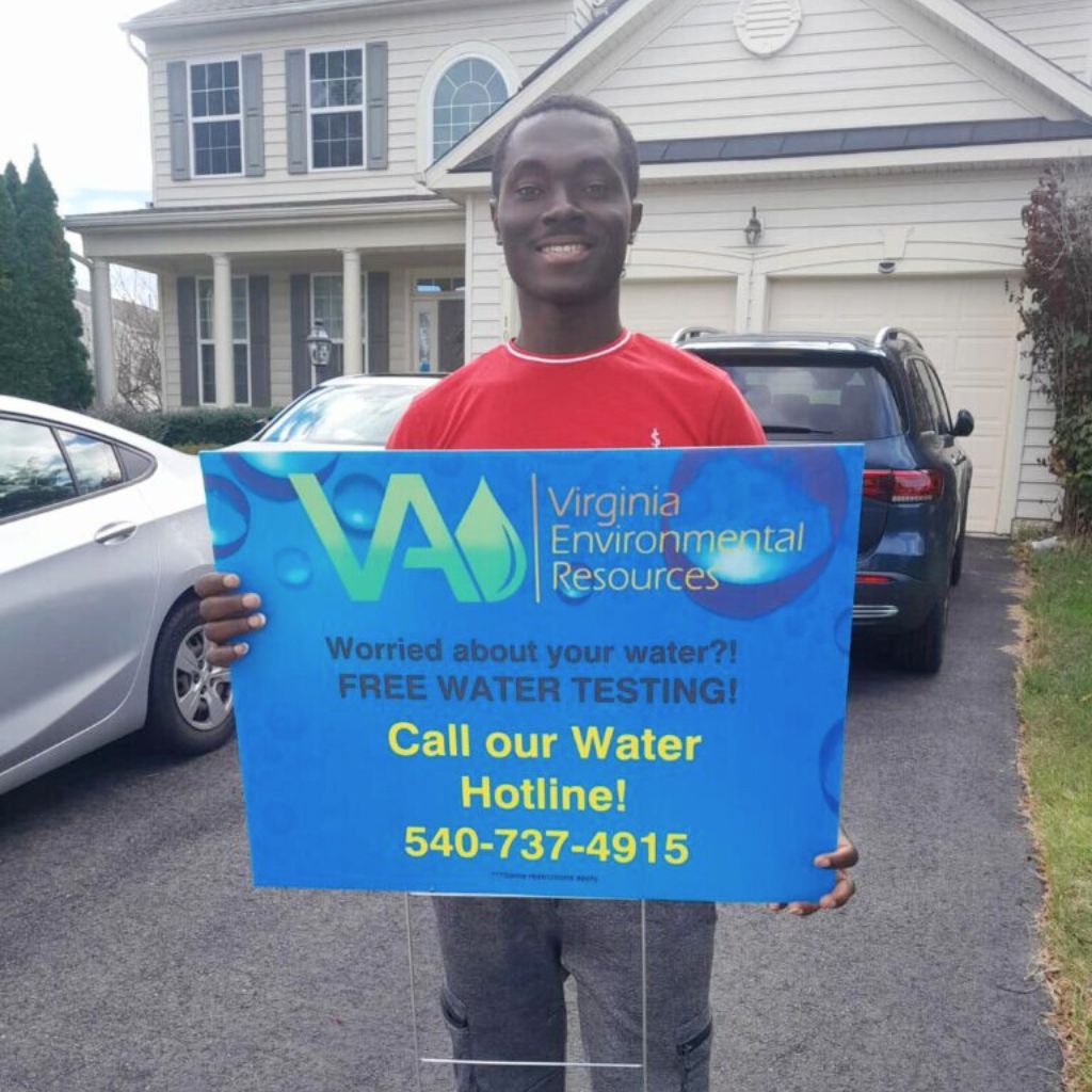 Happy customer holding Virginia environmental solutions sign, free water testing