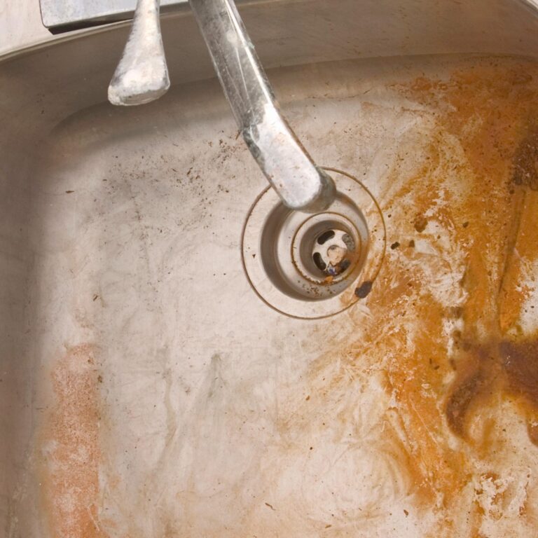 a dirty sink with brown rust stains from Iron in the water supply